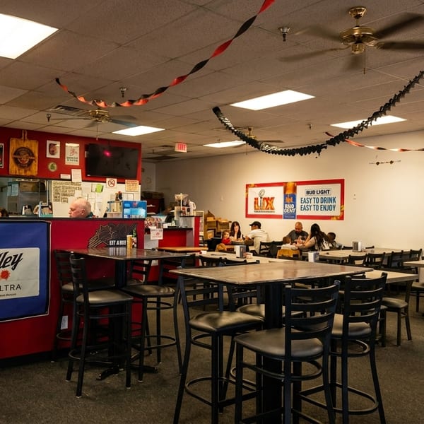 Interior of a casual restaurant with high-top tables, ceiling fans, and patrons dining.